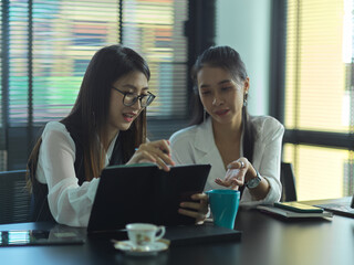 Two female businesspeople consulting on their project in meeting room