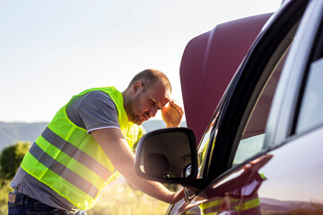 Photo of man looking under the hood of breakdown car at outdoor.Stressed man having trouble with...