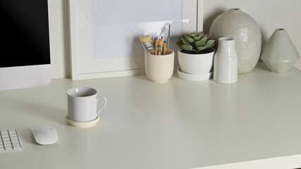 Worktable with computer device, mock up frame, decorations and copy space