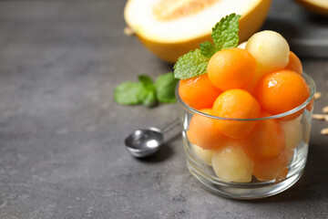 Melon balls and mint in glass on grey table, closeup. Space for text