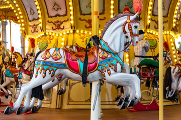 Colorful carousel horse on a vintage illuminated roundabout carousel (merry go round) in a park in...
