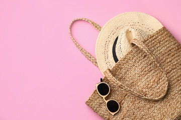 Elegant woman's straw bag with hat and sunglasses on pink background, top view. Space for text - obrazy, fototapety, plakaty