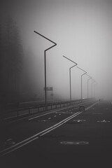 Dark road with double lines disappears into very thick fog