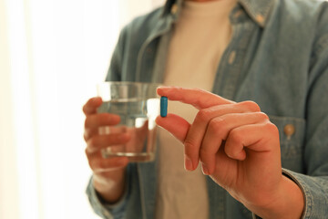 Woman hold glass of water and blue pill capsule