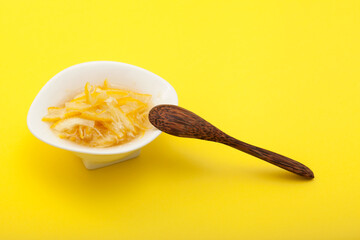 Sliced lemon with honey or sugar in a white bowl. Base for citron or herbal tea. Yellow background, copy space