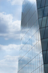 Blue cloudy sky reflected in the exterior glass facade of a modern corporate building