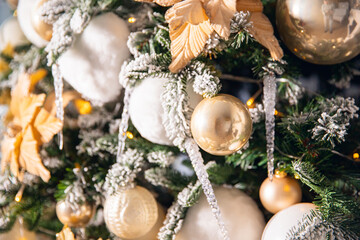 Christmas background in light and gold tones, New Year tree decorated with balls and artificial snow illumination