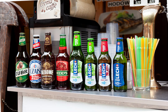 Set of Polish beer bottles in a row, various brands, many alcohol bottles and plastic straws in container Żubr, Leżajsk, Dębowe, Lech, Redd's and 0% beer
