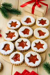 Christmas or new year linzer cookies in the shape of stars and bells with jam on a wooden background