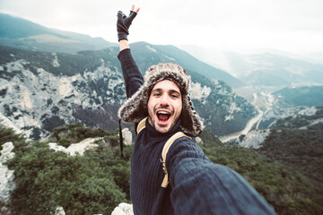 Handsome happy hiker taking a selfie on the top of the mountain - Smiling guy trekking outdoor at...