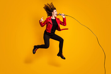 Fototapeta na wymiar Full length body size view of cheery cool crazy wavy-haired girl jumping singing showing horn sign isolated on vibrant yellow color background