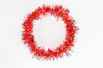 Round circle of bright red tinsel on a white background. Christmas decorations. New year concept