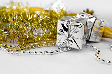 Silver little gifts, shiny yellow golden tinsel, toys, beads. New year decorations on a white background. Christmas concept.