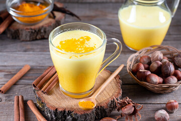 Golden milk with turmeric in a glass cup on a wooden background.