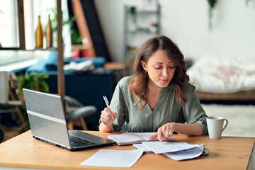 Young woman working from home office. Freelancer using laptop and the Internet. Workplace in living...