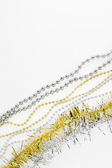 Silver and golden chain with balls, beads, yellow tinsel. New year decorations on a white backdrop. Christmas concept. Template for text. Diagonal