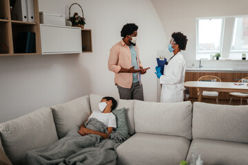 Fototapeta premium Doctor having consultation with man whose son is sick and lying on bed near them