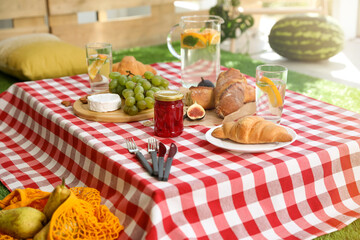 Different tasty food on picnic blanket at home