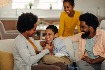 Afro parents and their children bonding at home. They are laughing and tickling together