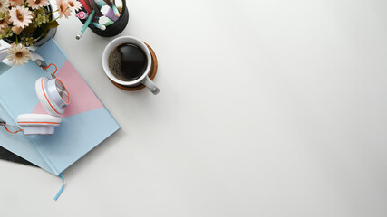 Top view of minimal designer workplace with headphone, coffee cup, notebook  and stationery.on white table with copy space.