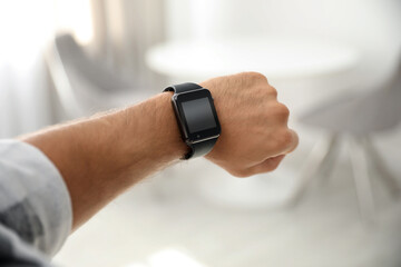 Man with smart watch on blurred background, closeup
