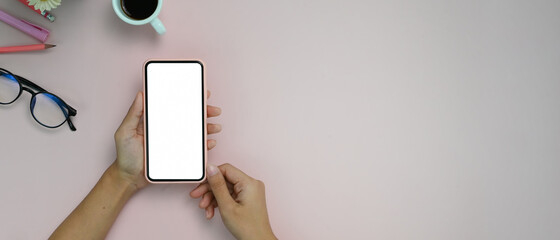 Top view of young woman holding mock up smartphone on his working desk with copy space.