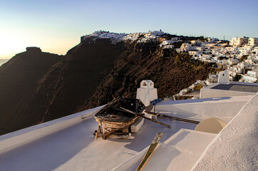 Old wooden boat on the white rooftops of Santorini, Greece