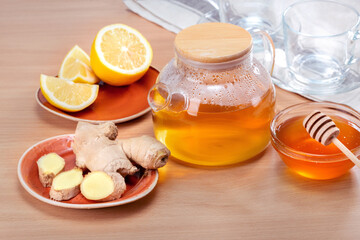 Ginger tea ingredients concept. Teapot with hot tea on wooden table.
