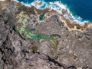 Aerial view of Los Charcones a hidden Lanzarote gem. A stunning natural infinity pool on a lava soil, close the Atlantic ocean. Bathers. Swimming. Canary Islands, Spain