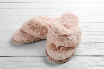 Pair of stylish soft slippers on white wooden background