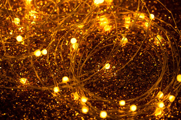 Led lighting close up image. Beautiful yellow Christmas and New Year garland is glowing on a glitter paper