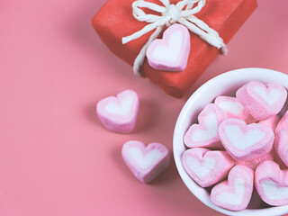 flat lay of heart shape marshmallows in white cup  on wth red gift box on pink background with copy...