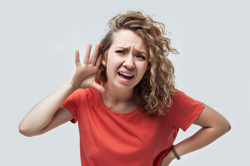 Image of pretty blonde girl holding hand near ear trying to listen something. Human emotions,...