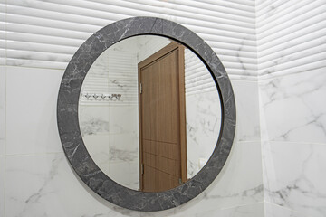 Round mirror on marble wall in luxury bathroom