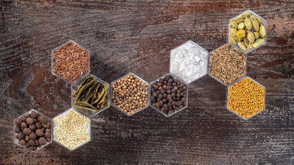 Spices in hexagonal jars on a wooden surface