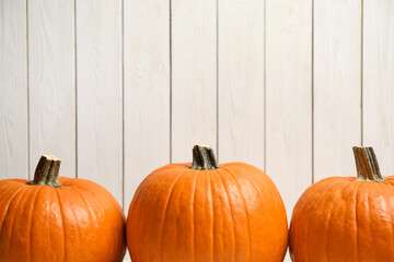 Ripe orange pumpkins against white wooden background. Space for text