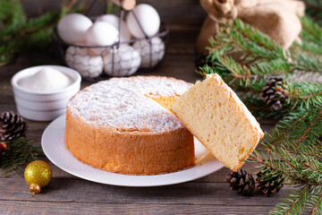 Homemade round sponge cake or chiffon cake on white plate so soft and delicious with ingredients: eggs, flour, milk on wood table. Basis for making holiday cakes and desserts. 