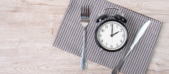 Top view alarm clock with knife and fork on table cloth background. Intermittent fasting, Ketogenic dieting, weight loss, meal plan and healthy food concept