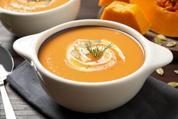 Tasty creamy pumpkin soup with dill and seeds in bowl on table