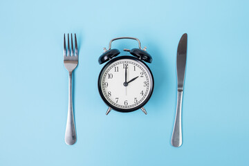Top view alarm clock with knife and fork on blue background. Intermittent fasting, Ketogenic...