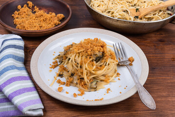 Spaghetti alla carrettiera, pasta with onions and breadcrumbs in a plate on a rustic wooden table