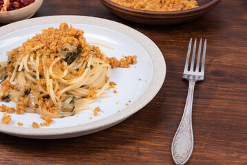 Spaghetti alla carrettiera, pasta with onions and breadcrumbs in a plate on a rustic wooden table