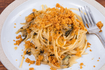 Spaghetti alla carrettiera, pasta with onions and breadcrumbs in a plate close-up on a rustic...