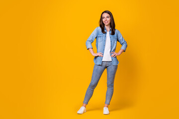 Full length photo of attractive pretty confident lady arms by sides good mood adorable appearance look side empty space wear casual denim shirt shoes isolated vibrant yellow color background