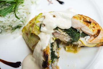 Fillet of white fish sea bass, cod stuffed with greens and rice on the table in the restaurant.