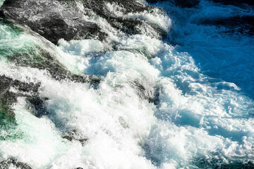 Wild and fast moving river rapids white water rushing over rugged cliffs. Close up. - Powered by Adobe