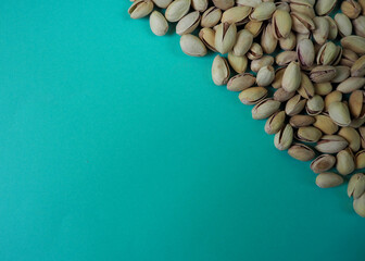 many grains of pistachios close-up top view on turquoise background