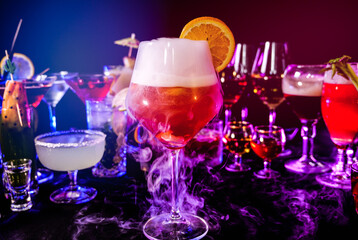 Aperol spritz drink with dry ice at bar counter close up. Bartender show and prepared cocktail with dry ice on a cocktail bar background. Colorful various drinks in a bar with dry ice smoke effect.