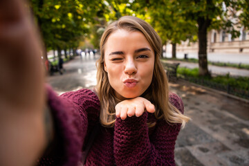 Smiling woman taking a selfie on phone in an urban street