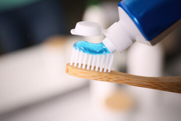 Applying toothpaste on brush against blurred background, closeup